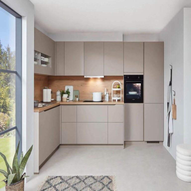 Musterküche in Kaschmir als L-Küche mit Holzrückwand und Backofen im Hochschrank – Küchenstudio Bremerhaven